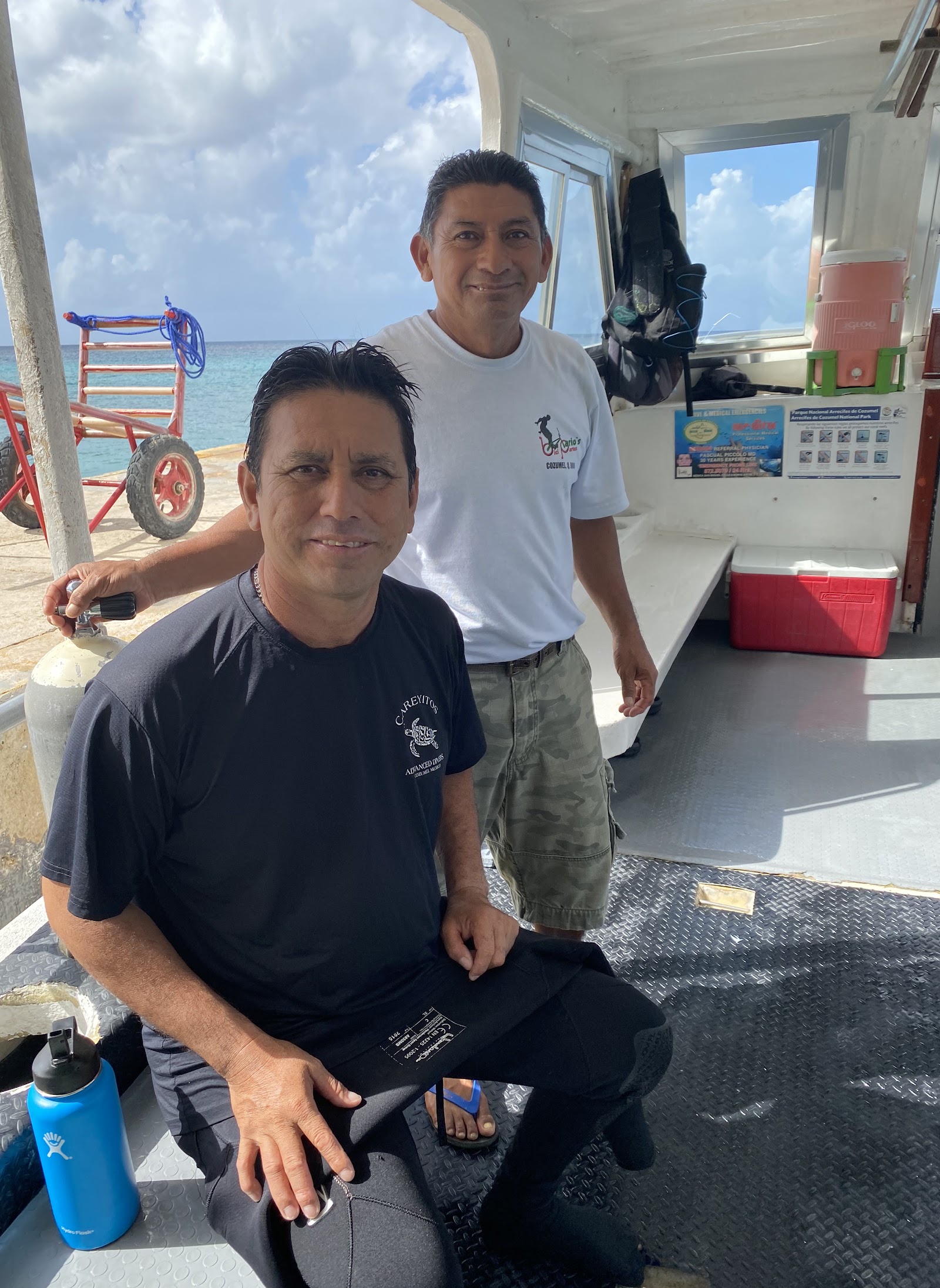 Two Careyitos crew members on the back deck of the boat, one wearing a Careyitos Advanced Divers shirt